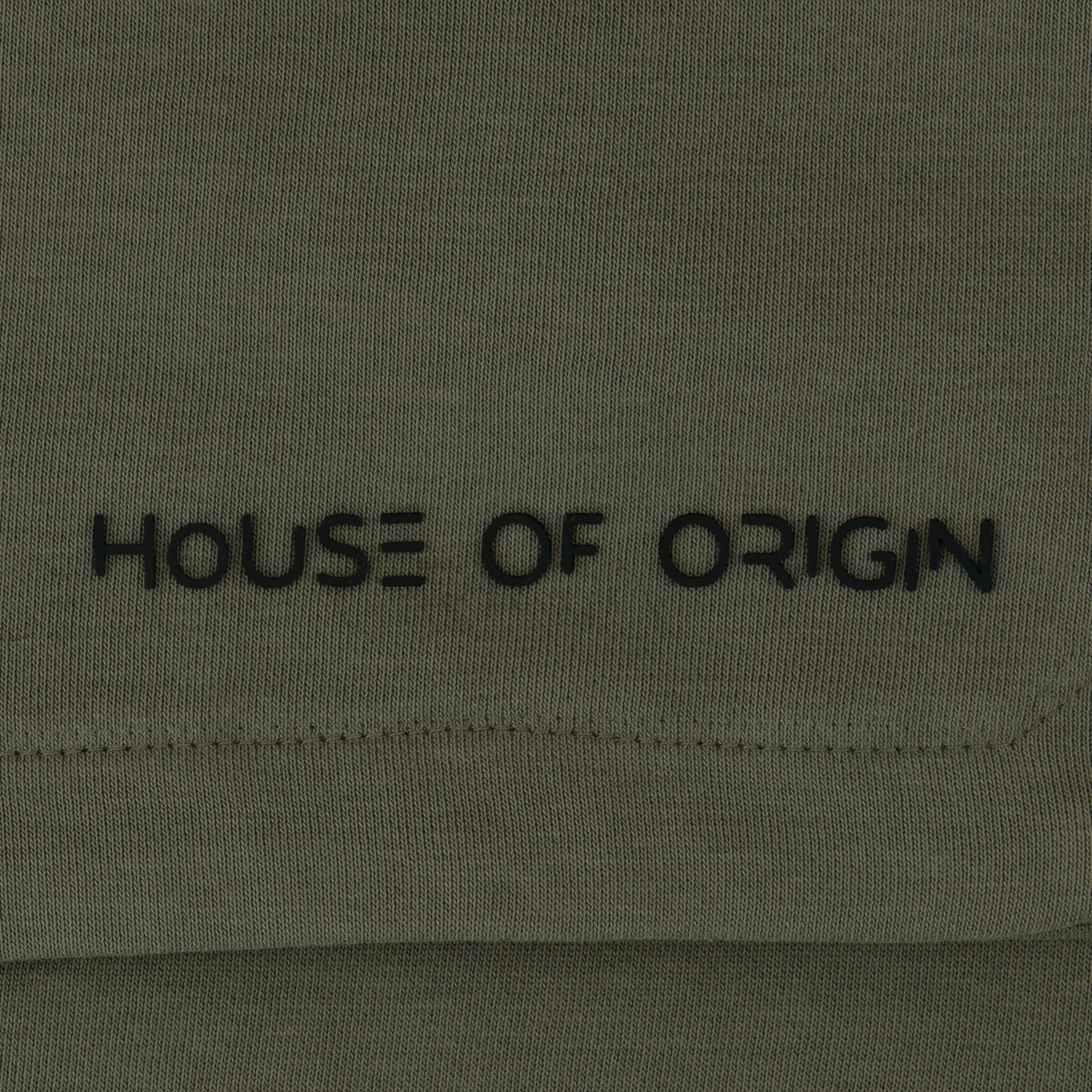 Green fabric with 'HOUSE OF ORIGIN' embroidered in black